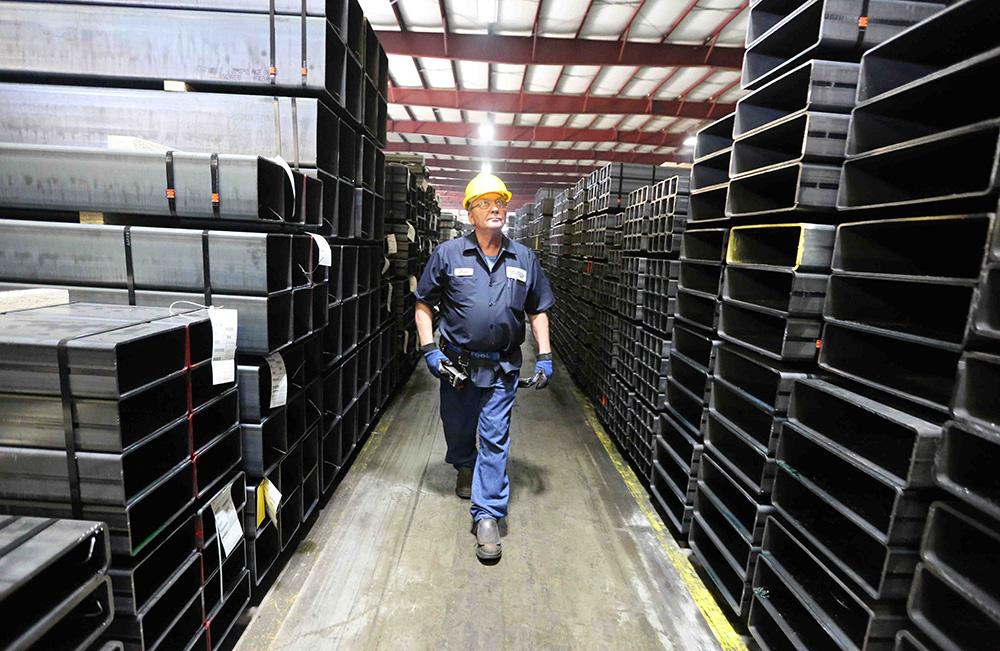 Bull Moose Employee Walking in plant past different tubes