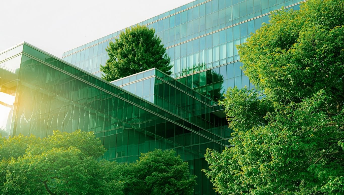 BMT - Blog 3 A modern green glass building surrounded by trees, highlighting eco-friendly Hollow Structural Steel.