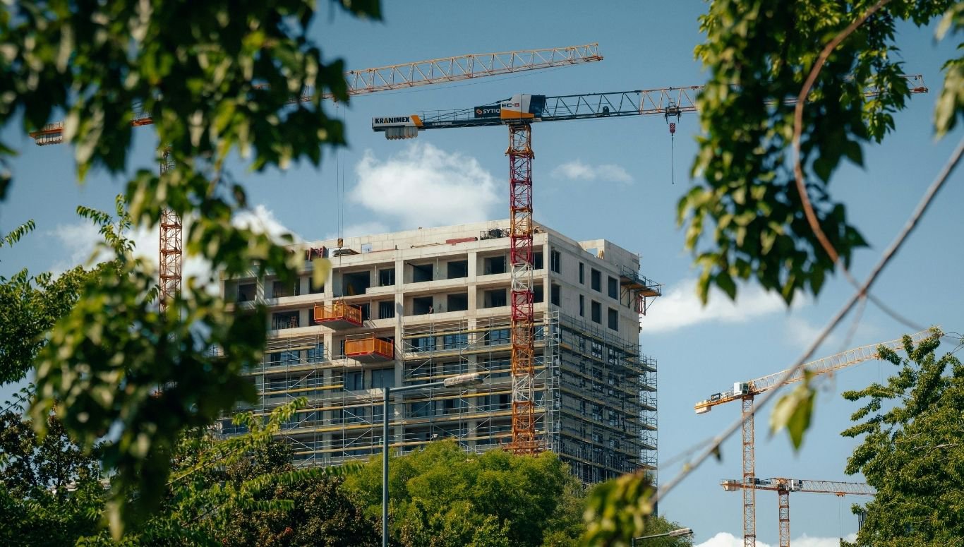 Construction cranes towering over a building development utilizing structural carbon steel pipe.