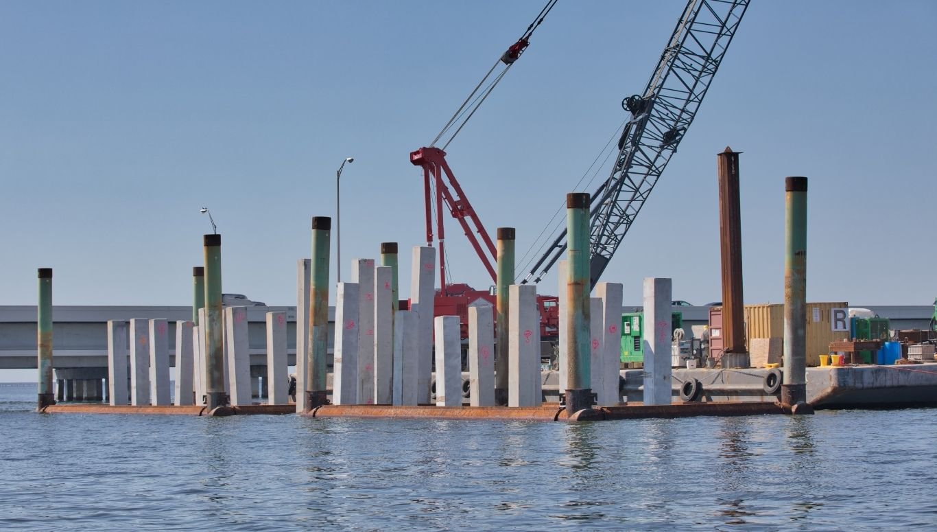 BMT - Blog 3 A coastal construction site with cranes and a barge preparing a structural pipe pile foundation.